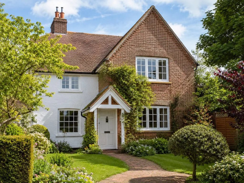 White and brick cottage with a curved brick path through a front garden